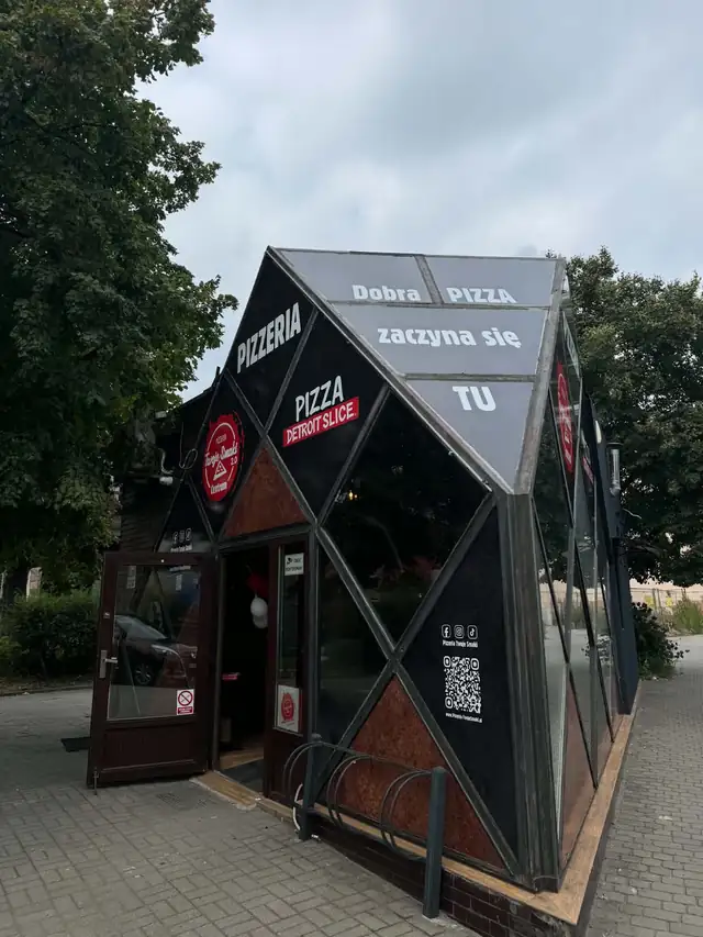 Czarny szklany pawilon pizzerii z napisem „Dobra pizza zaczyna się tu”